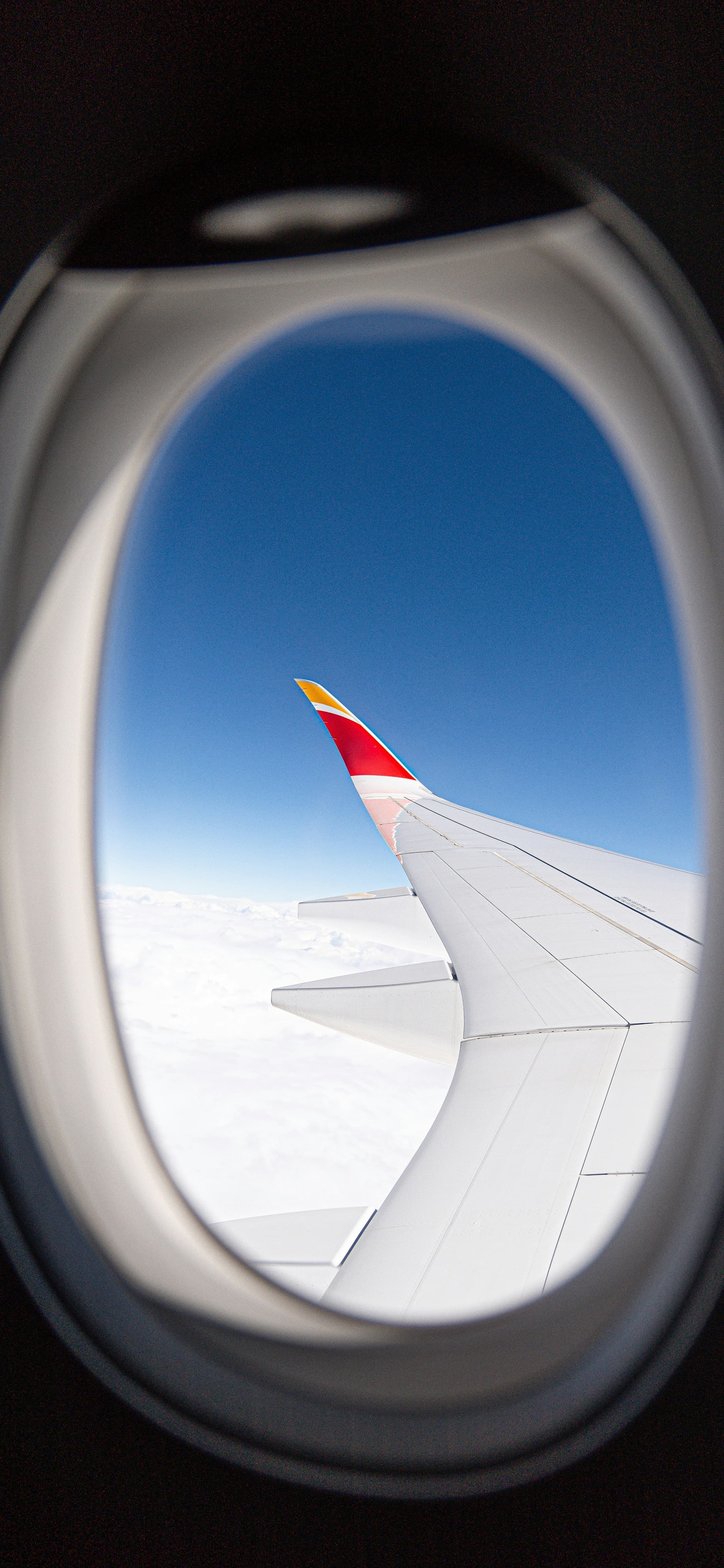 Blue sky and an aircraft wing seen through a window